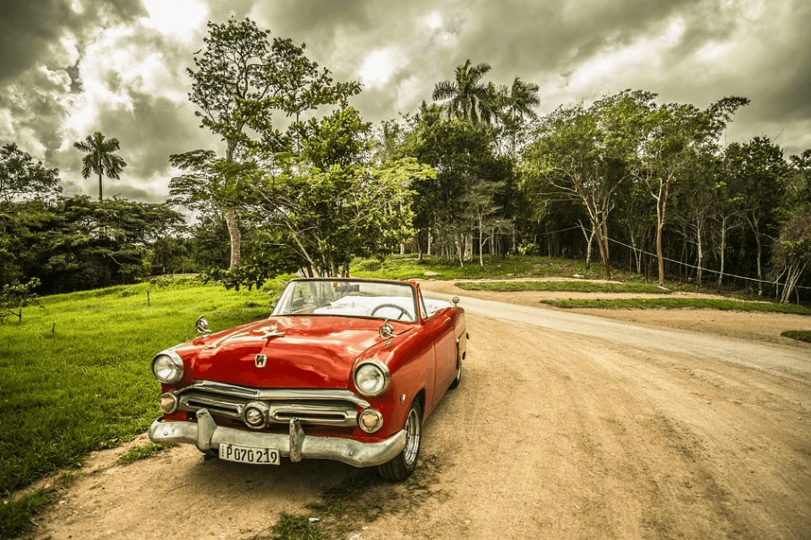 a red vintage convertible on a dirt road