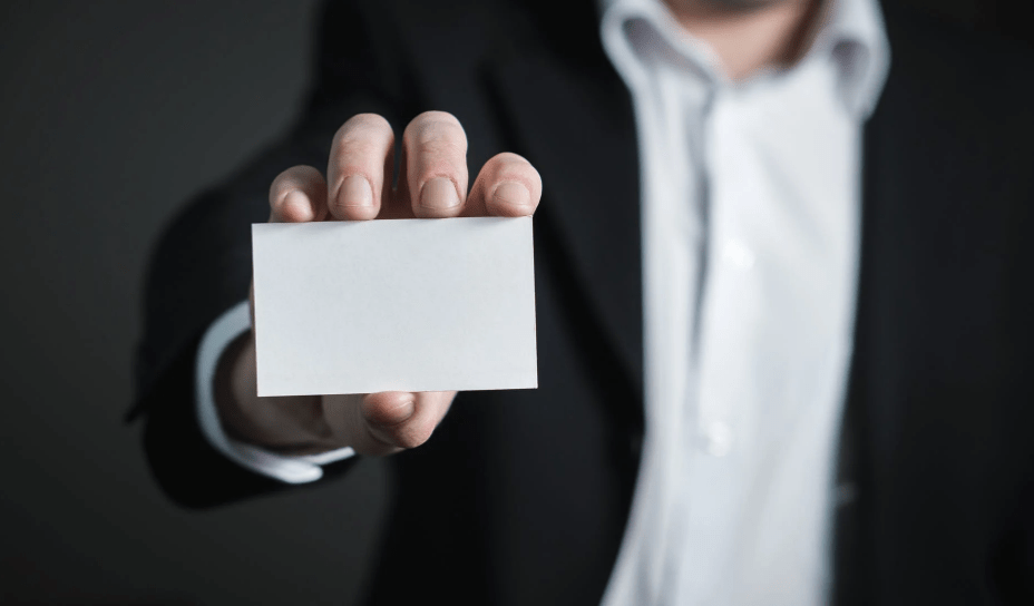 A guy holding out a blank business card in front of him.