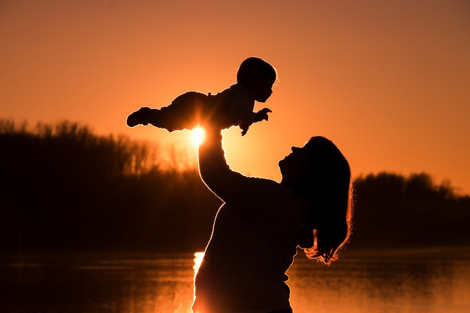 Silhouette of mother and baby against a sunset