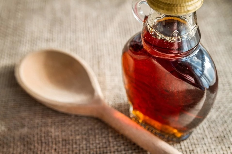 a bottle of maple syrup and a wooden spoon