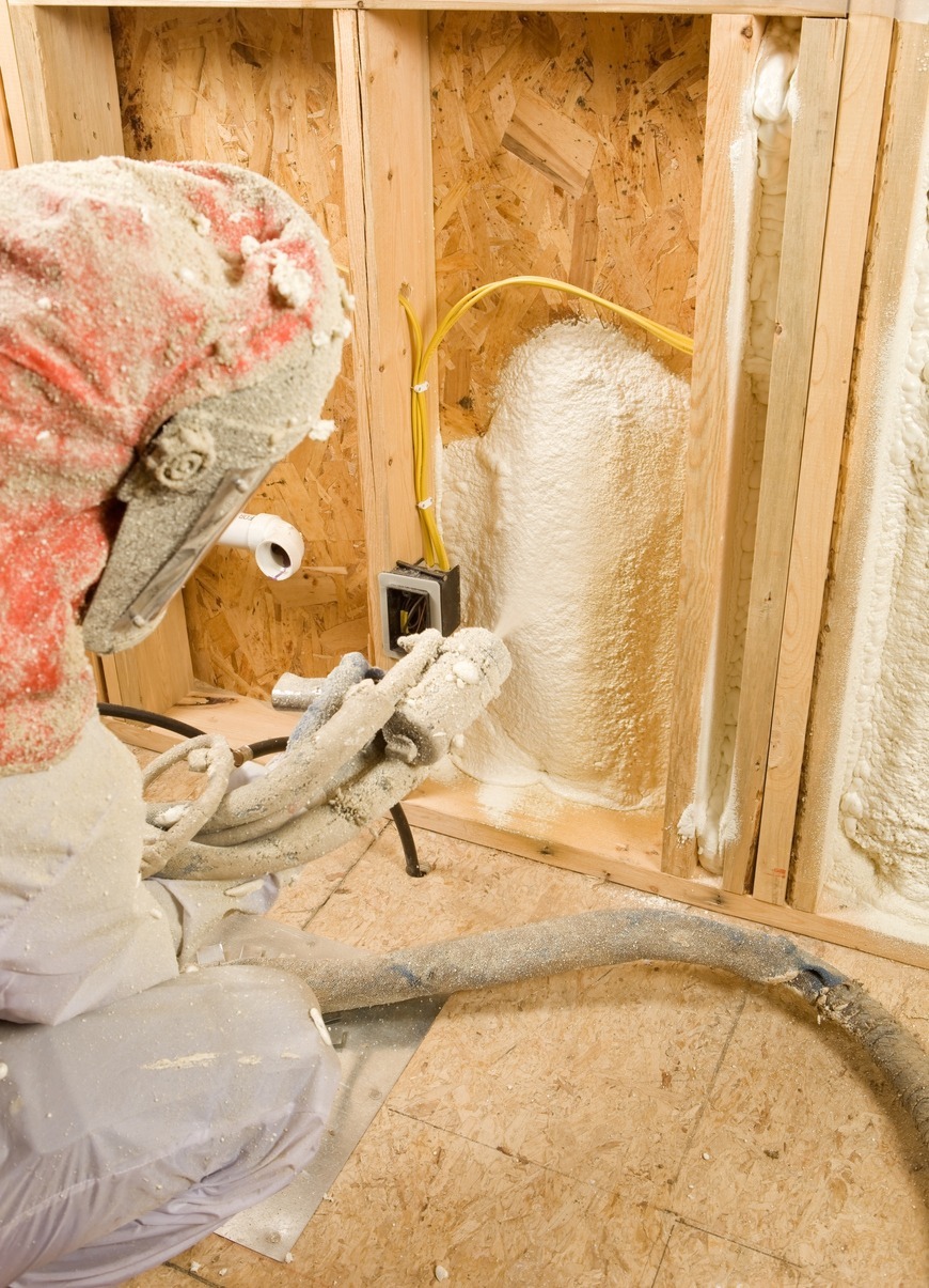 Construction Worker Spraying Expandable Foam Insulation Between Wall Studs