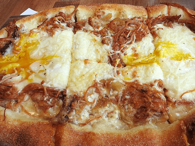 roasted pork belly pizza with eggs and caramelized onions