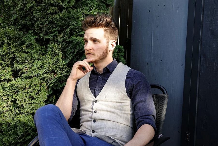 Stylish man wearing a vest and sitting outside