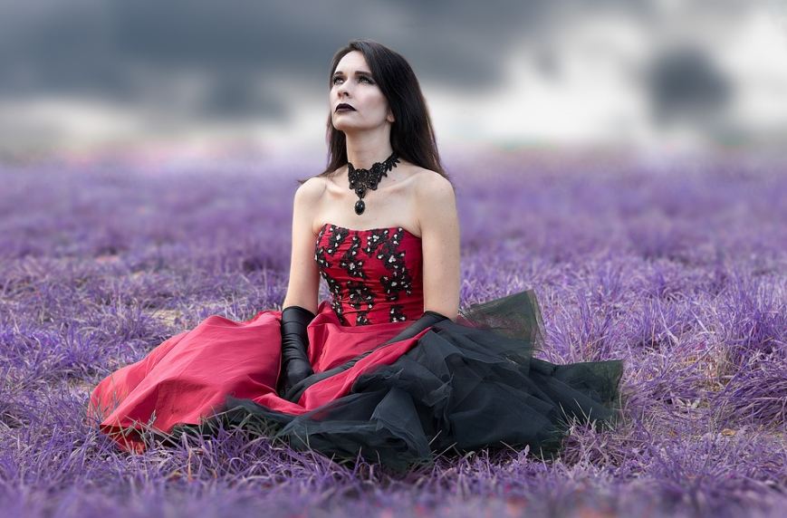 a gothic woman sitting on the grass