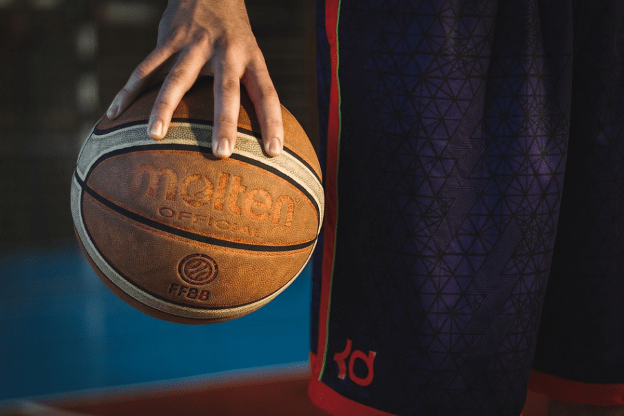 a hand holding an orange basketball 