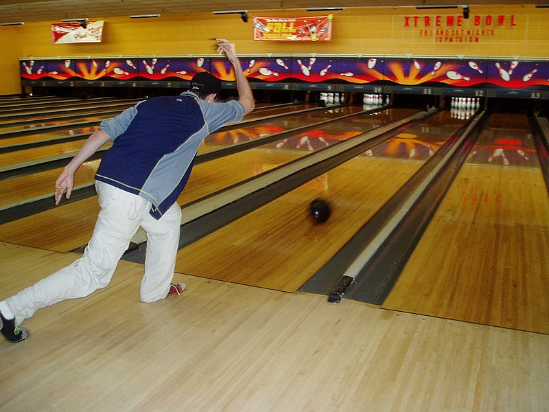 a ten-pin bowler releases his bowling ball inside a bowling game sport hall image