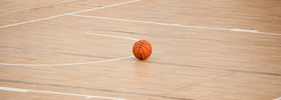 an orange basketball sitting on the floor of a basketball court