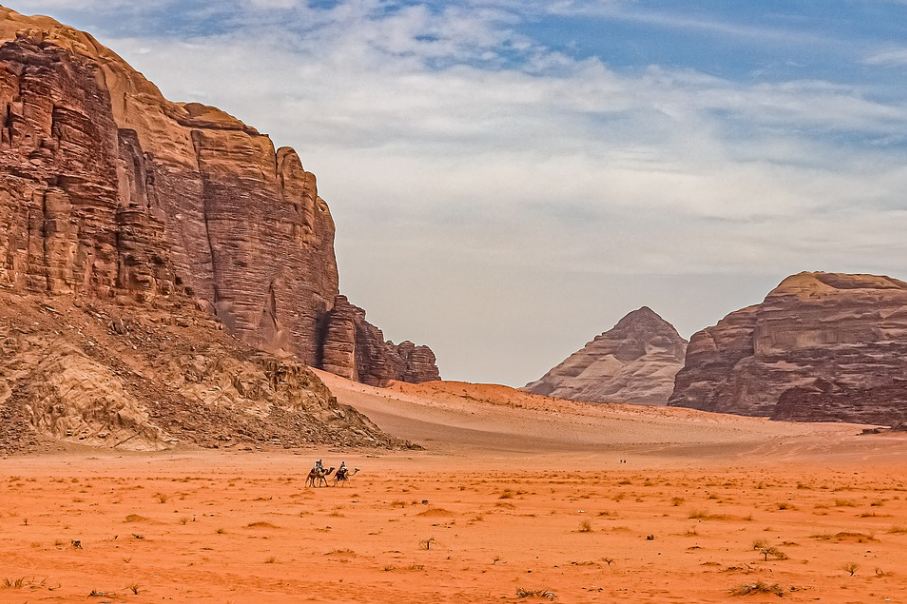 two camels on the red desert and tall rocky mountains