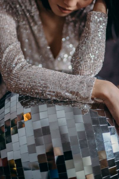 woman wearing gray glitter long sleeve dress beside a mirror ball