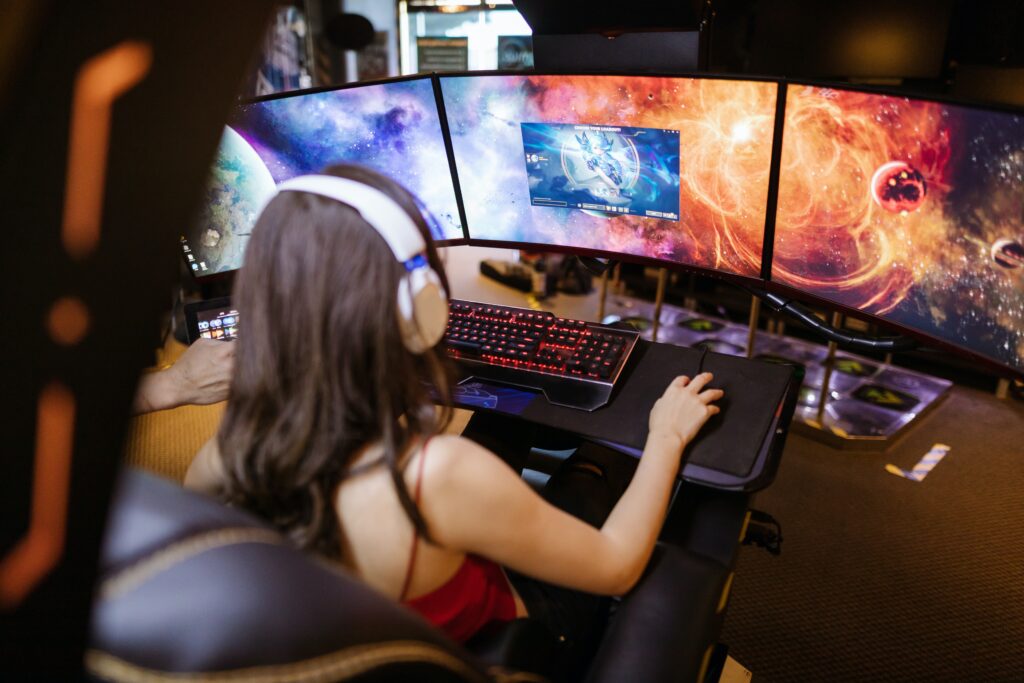 A woman playing games on a computer with three screens image