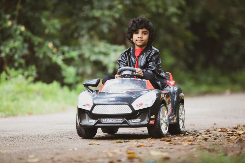 boy with curly hair driving a ride-on car image