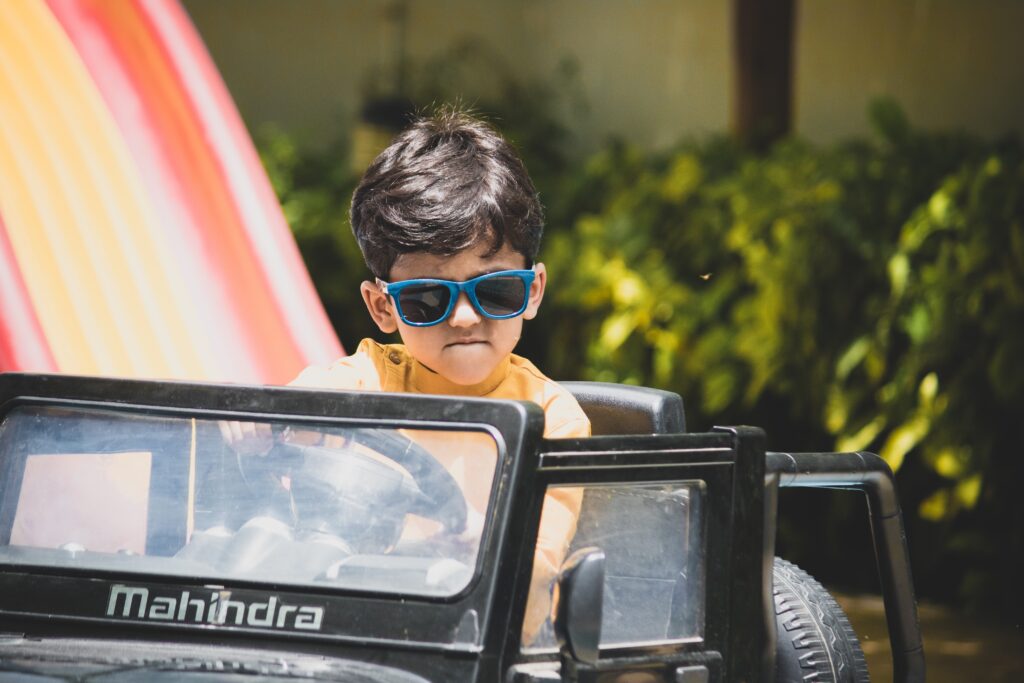 boy with sunglasses riding a ride-on car image