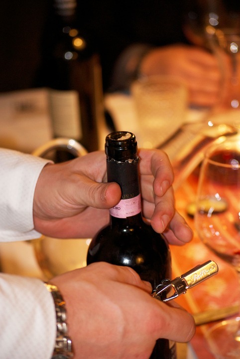 waiter pouring wine for guests at a table image