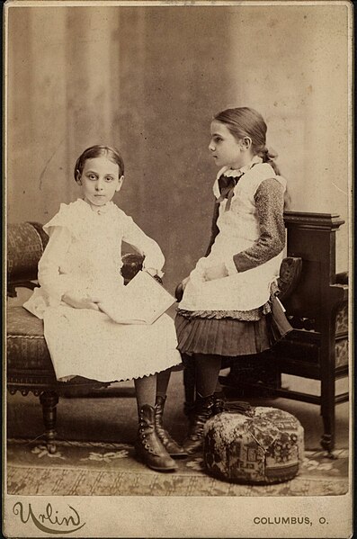 Two unidentified girls in dresses and buttoned up boots