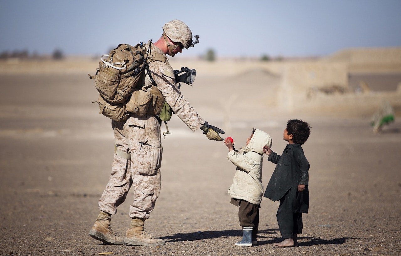 soldier being kind to two boys in a desert