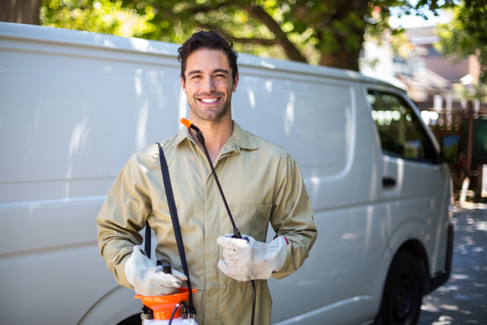 Portrait,Of,Smiling,Worker,With,Pesticide,Sprayer,While,Standing,By