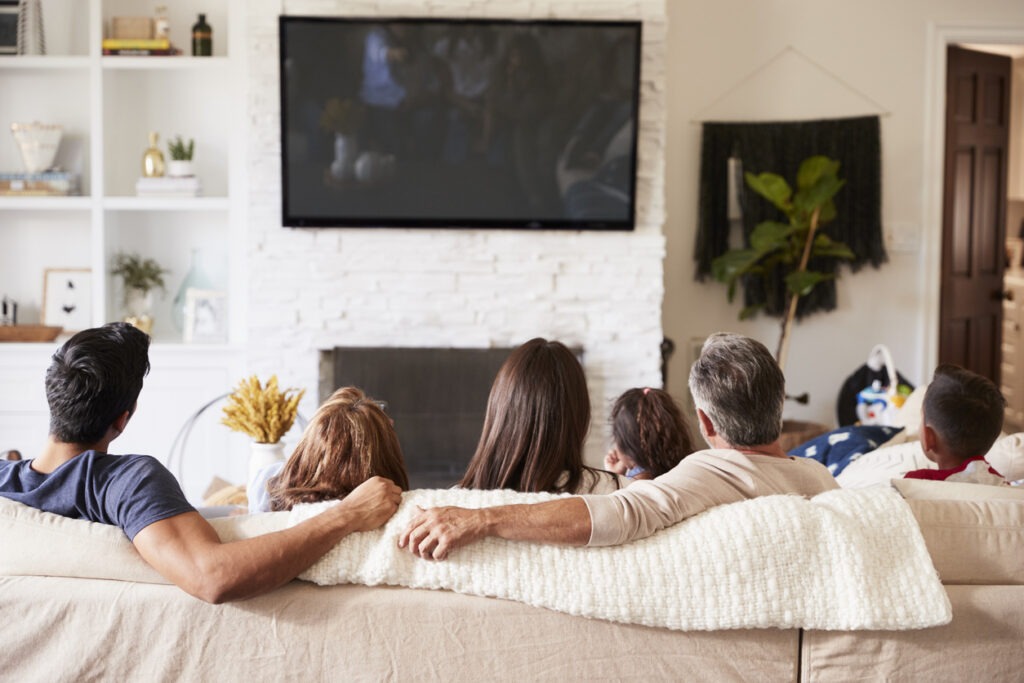 An image of a family sitting on the sofa watching TV