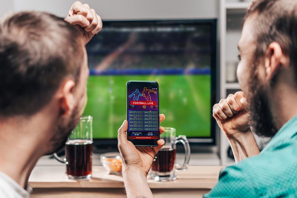 Two men watching live football while betting