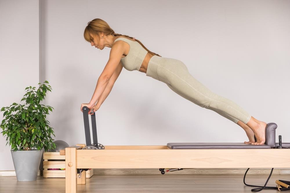 Woman training Pilates on the reformer bed