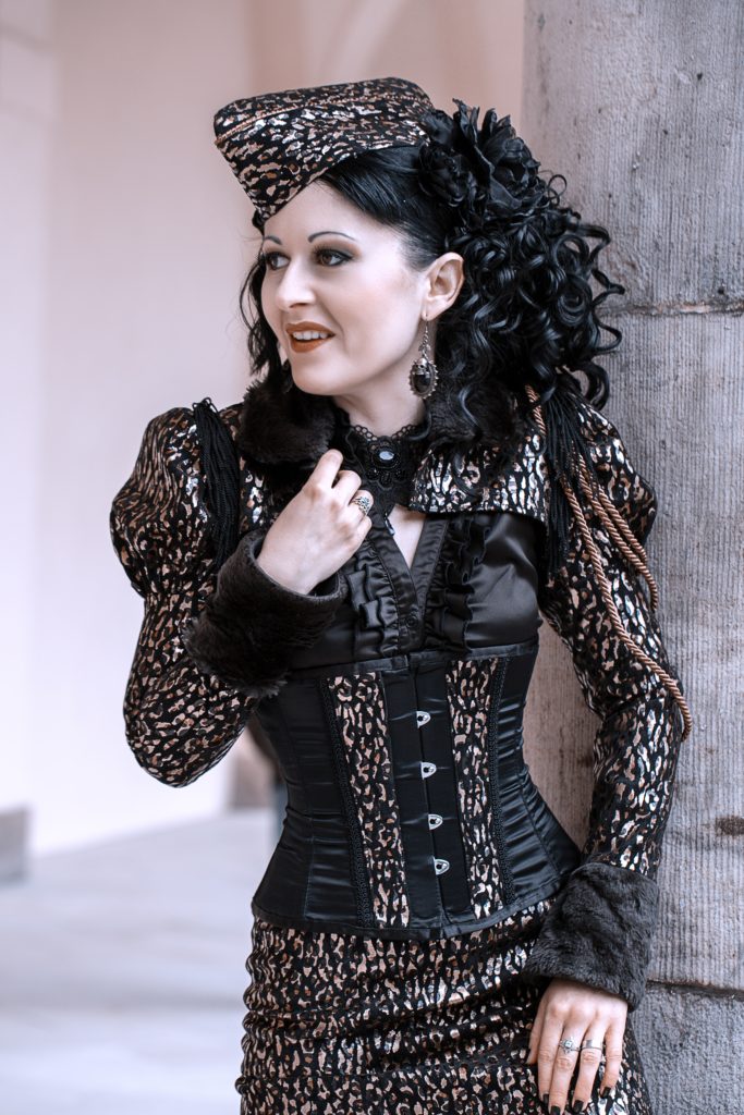  A Woman in Black Gothic Outfit Standing Near Gray Concrete Wall While Looking Afar