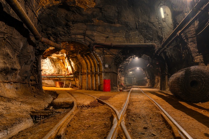 Tunnel of the mining of an underground mine. Lots of pipelines on the ceiling and rail track for trolleys