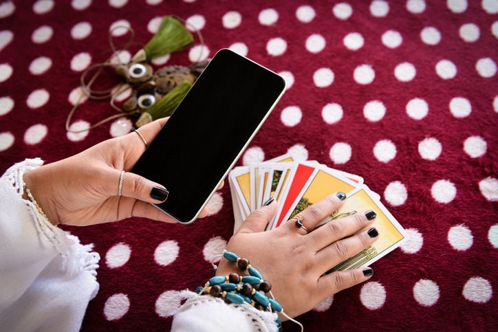 Fortune teller reading fortune lines on screen smartphone modern horoscopes online fortune telling application Palmistry Psychic readings and clairvoyance hands with Tarot cards divination
