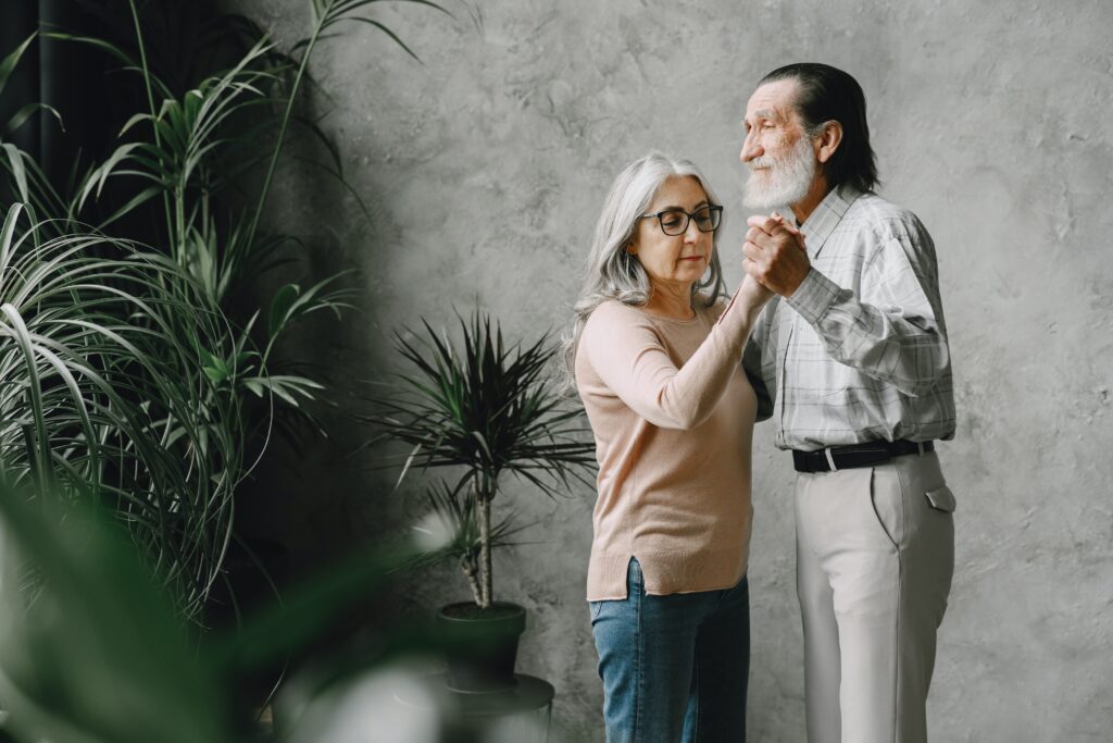 elder couple dancing together , with white background a plant in front of them image