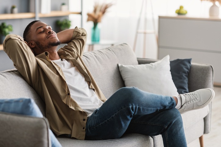 African American Guy Relaxing With Eyes Closed Sitting On Sofa Indoors