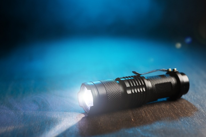 Tactical waterproof flashlight. LED flashlight shines on the table in smoke.