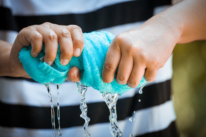 Woman hands squeeze wet blue towel and water drop