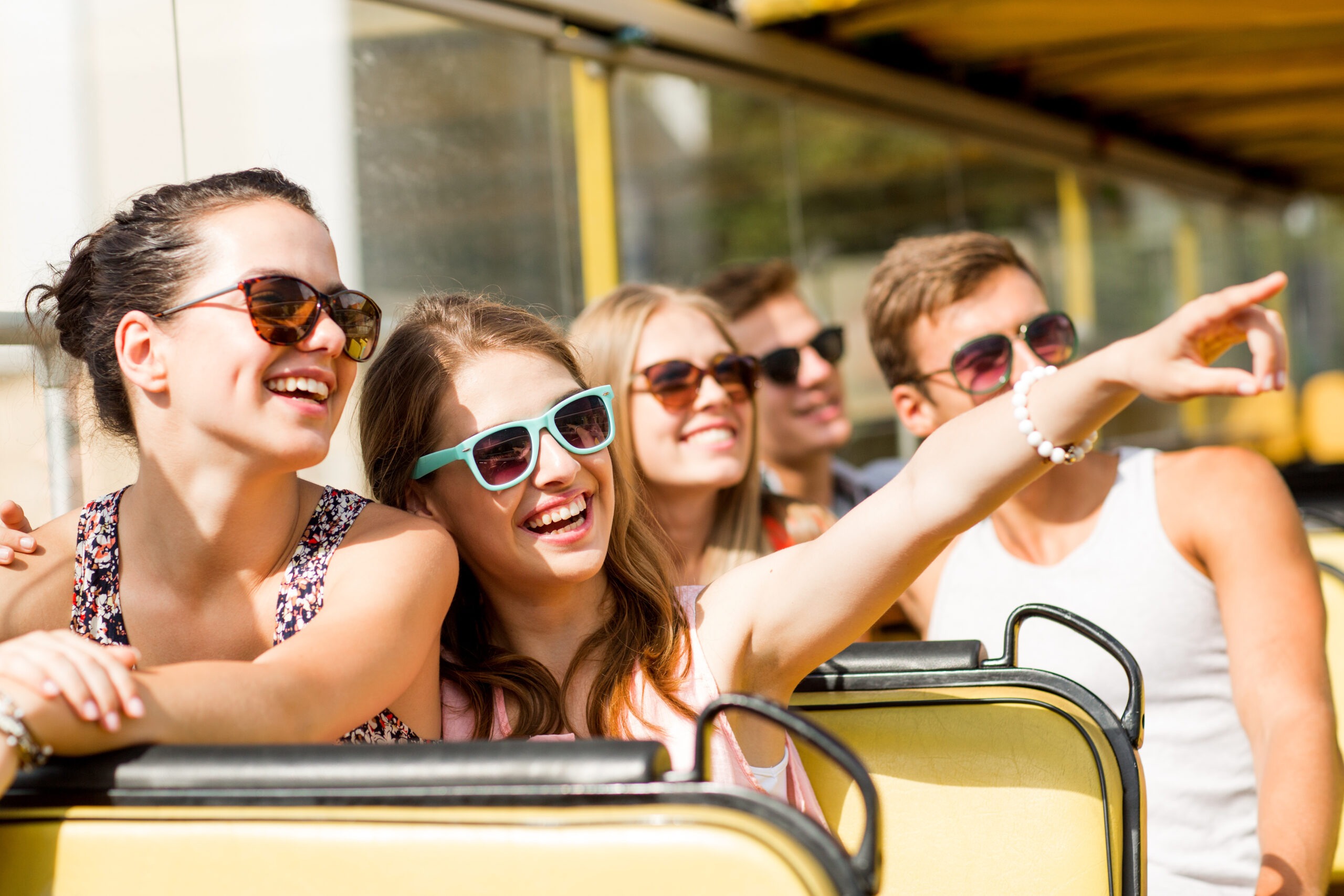 group of smiling friends traveling by tour bus