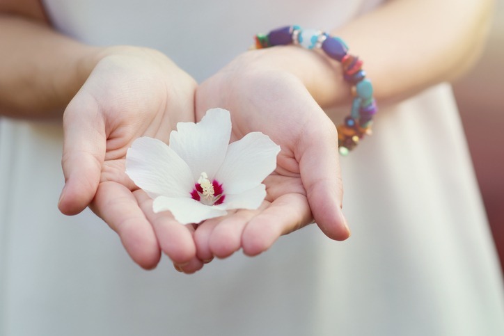 The girl holds a white flower in her open palms. A symbol of tenderness, femininity, chastity. Hands with a flower close-up. Copyspace