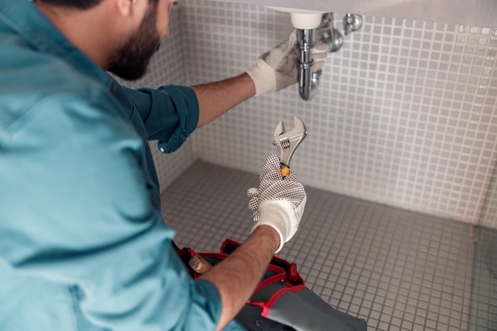 Close up of plumber is repairing faucet of a sink at bathroom using adjustable wrench