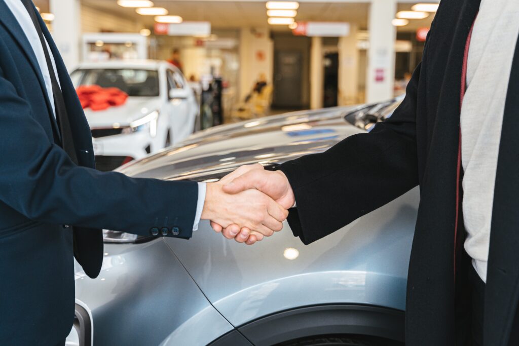 men shaking hands and cars in the background image