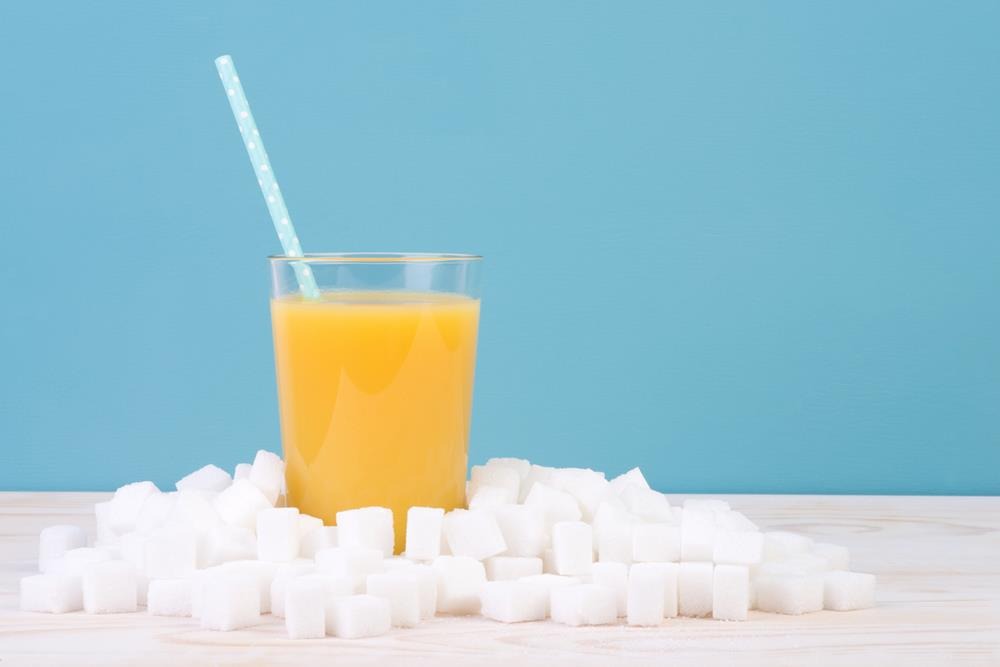 A glass of orange juice surrounded by sugar cubes