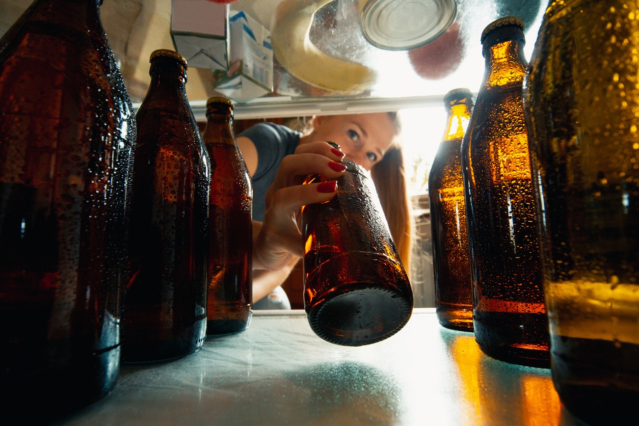 woman taking out a cold bottle of beer from the refrigerator