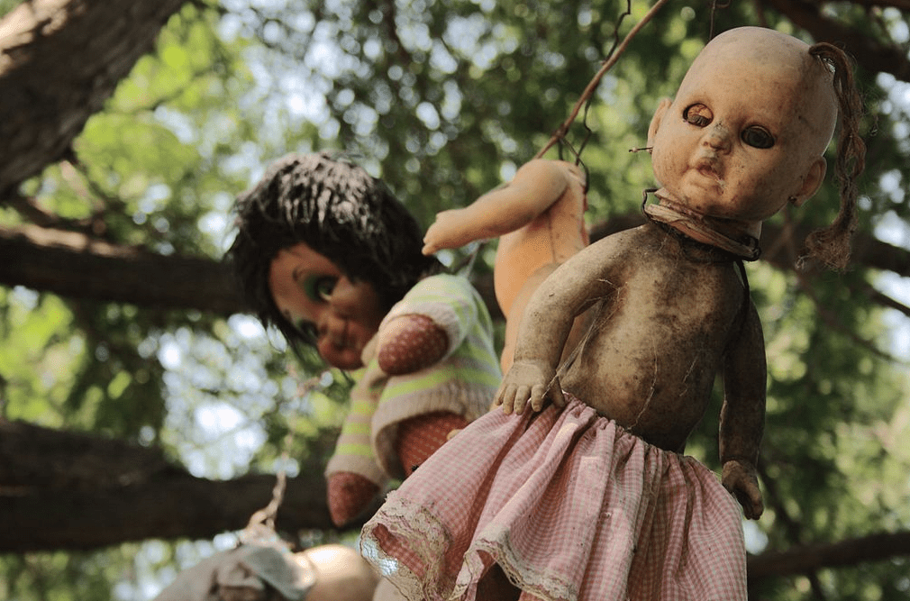 disfigured dolls hanging on a tree, scary decapitated doll