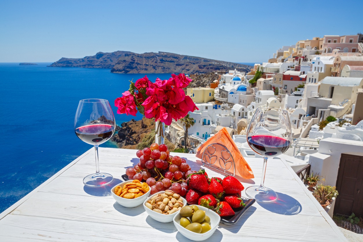 Wine, snacks and fruit on the table with a view of the Greek sea