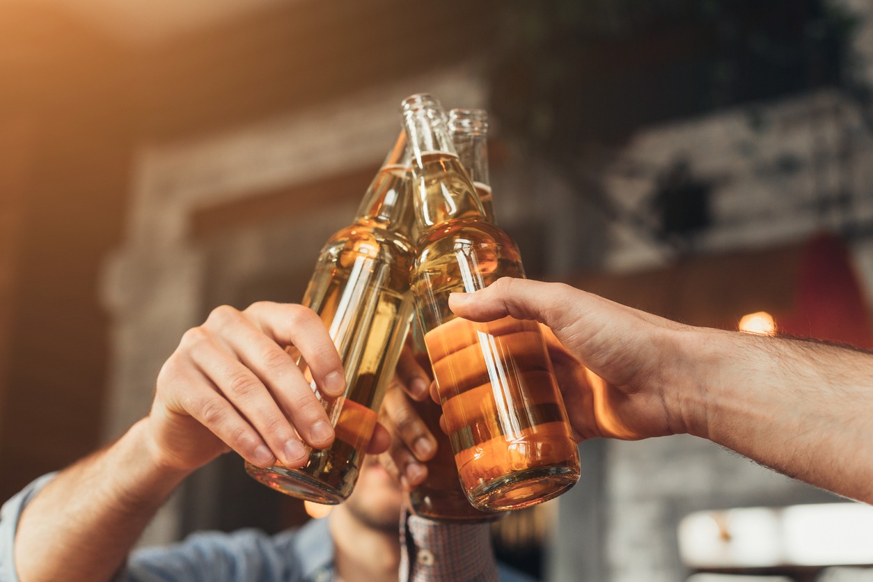 men clinking bottles together in a bar