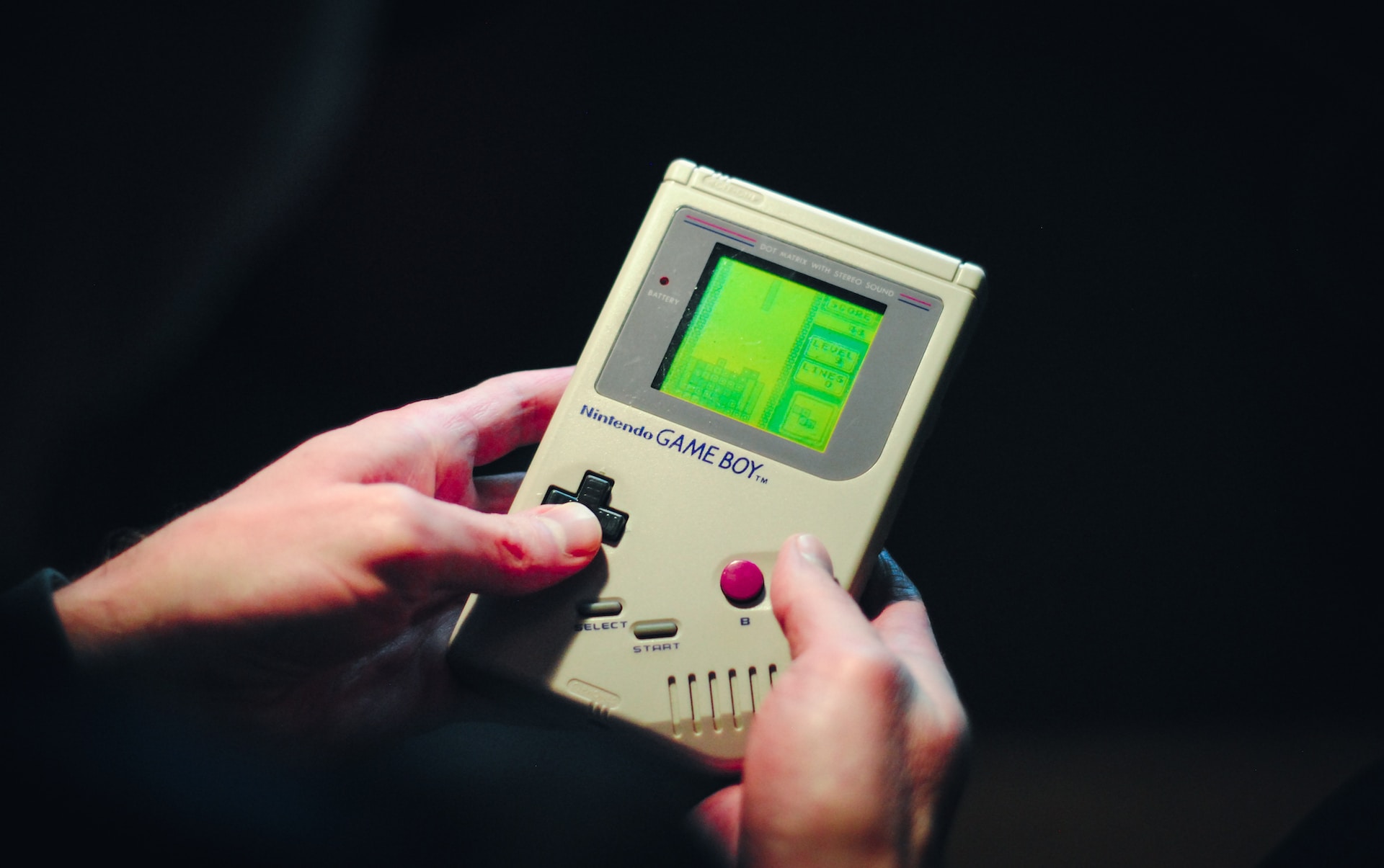 a person holding a Game Boy, playing Tetris