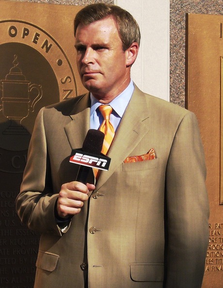 man in beige suit holding microphone