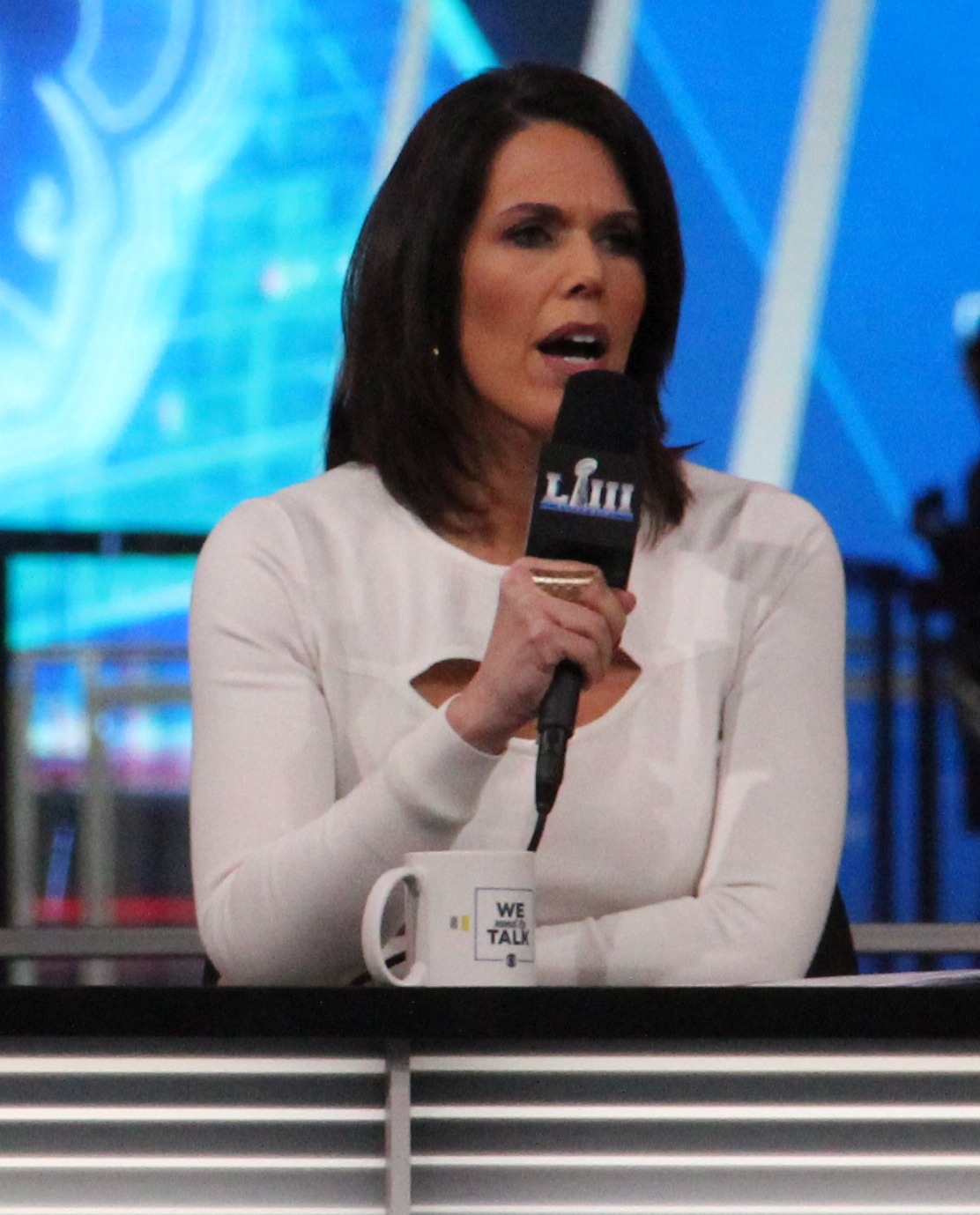 woman in white top holding microphone