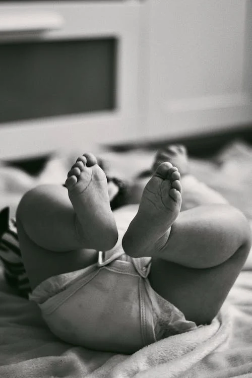 Feet of a Baby Lying on a Bed in Black and White 
