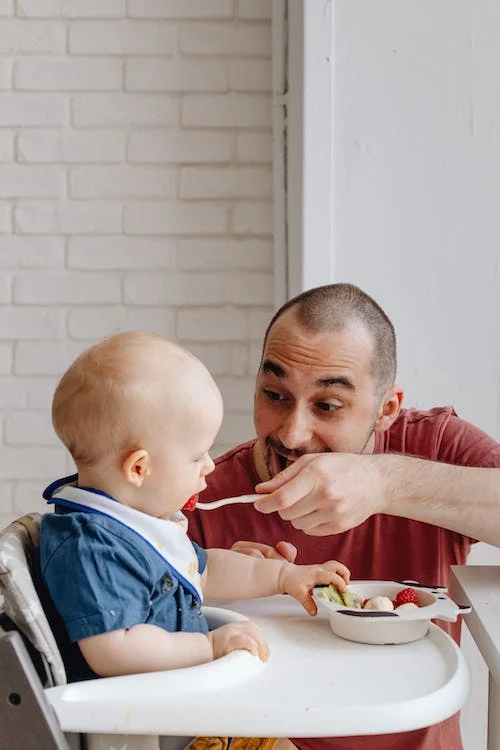 Man in Red Shirt Feeding Baby in Blue Shirt 