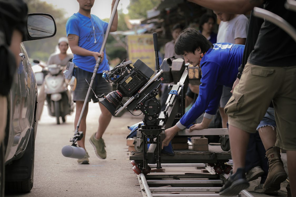man in blue shirt and brown pants holding a camera equipment