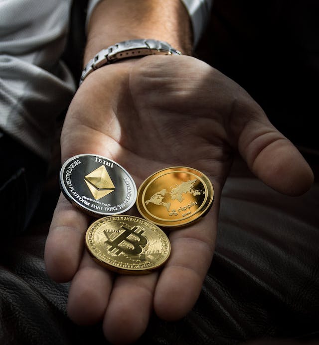 Person in a suit holding various cryptocurrency coins including Bitcoin and Ethereum in their outstretched hands against a white background