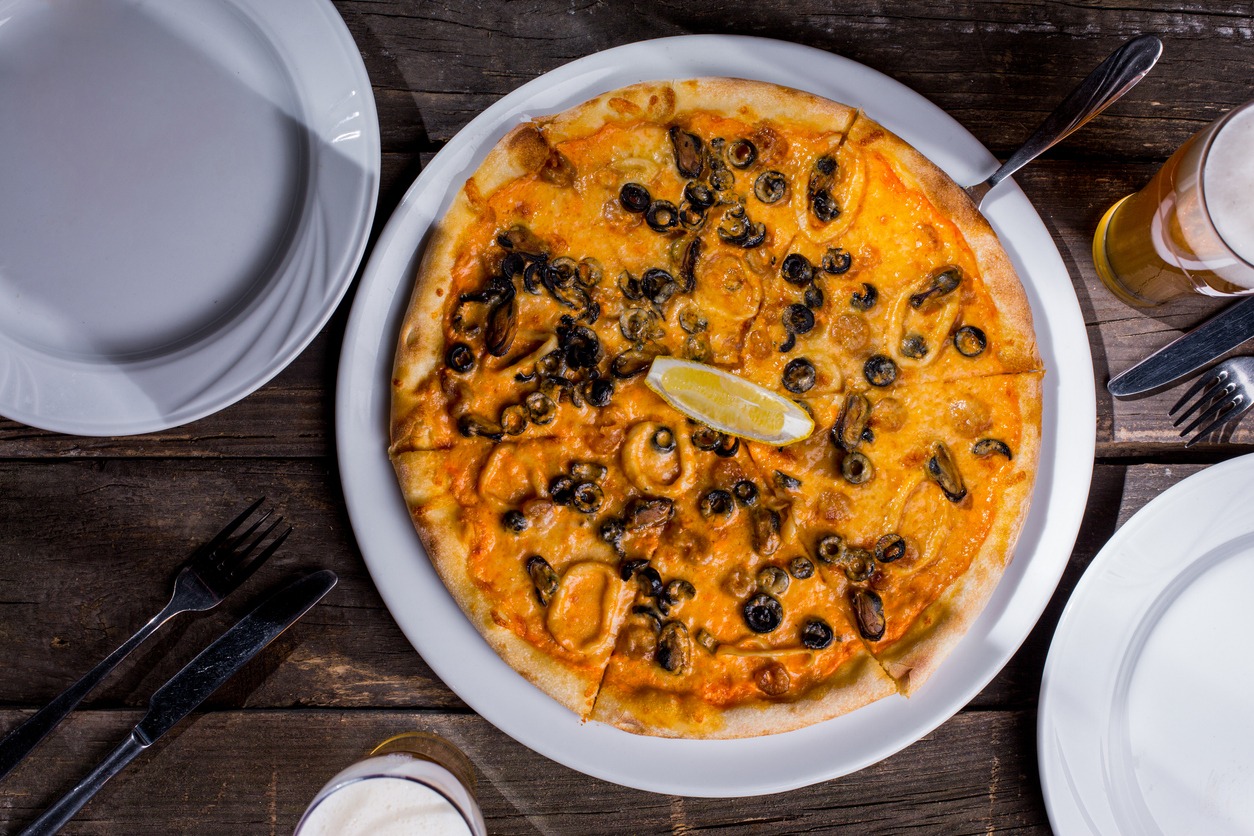 Pizza with mussels, squid rings, olives, lemon and cheese