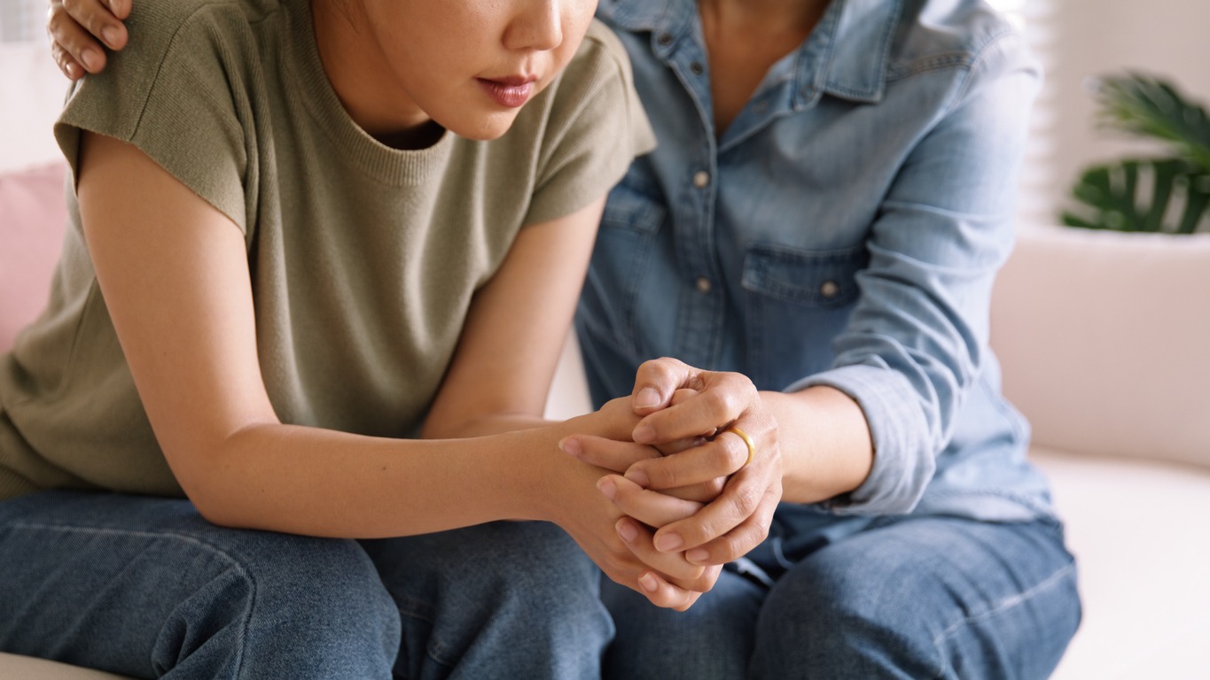 a woman holding hands with her teenage daughter who is stressed