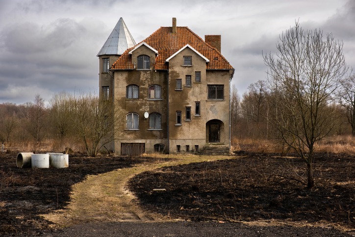 an abandoned house in the middle of a burnt field