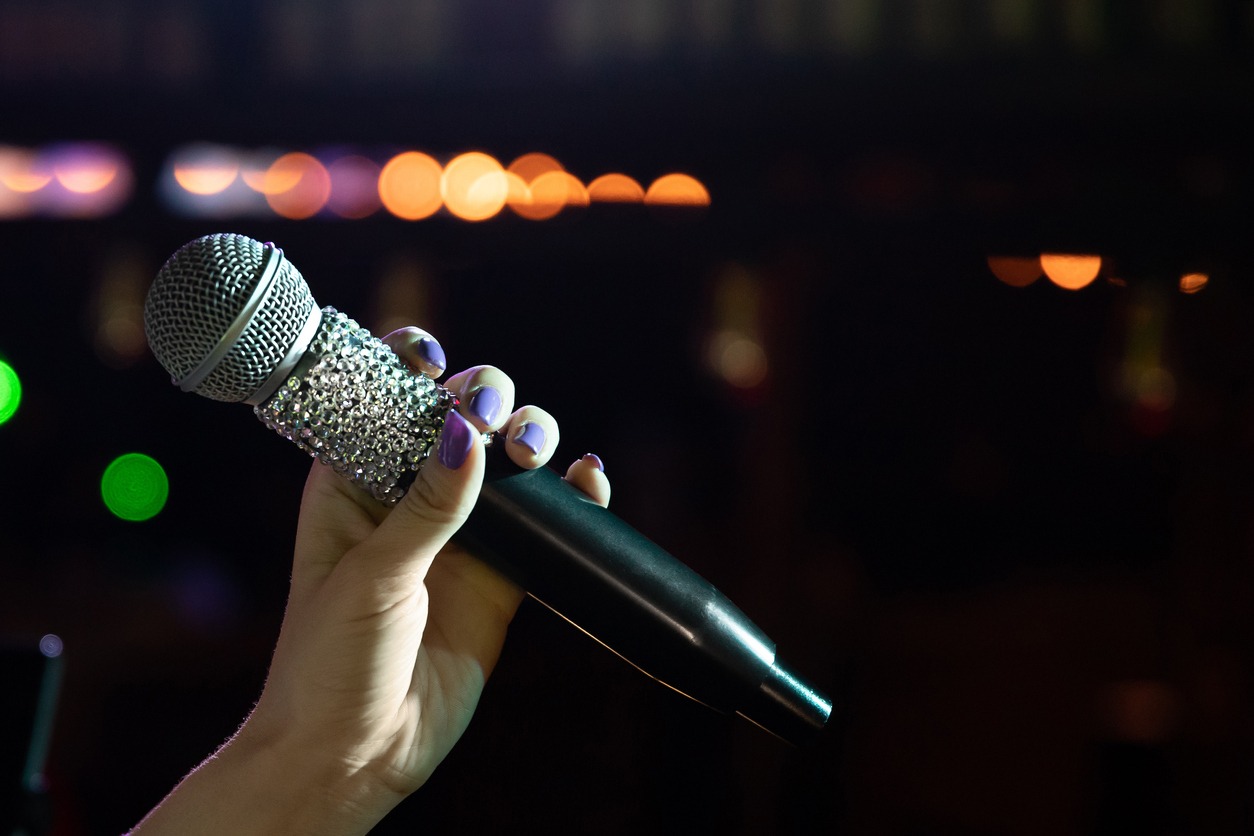 Close-up of woman hand holding microphone on stage copy space